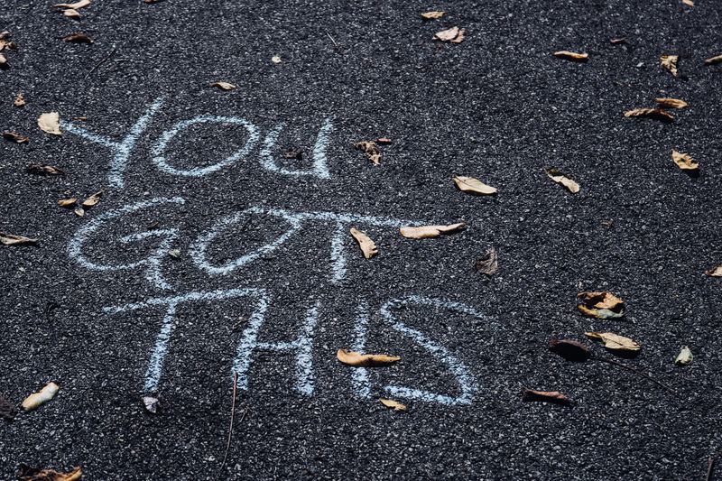 Blue chalk on asphalt that reads you got this