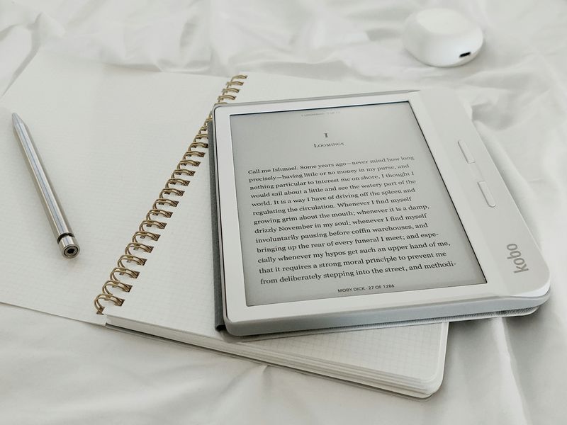 E-book on a white tablet on top of a blank notebook