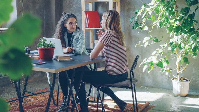 Two friends sitting at work talking.