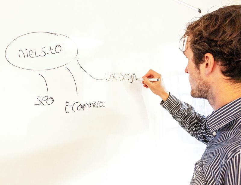 A man draws a mindmap on a whiteboard, with a central idea in a circle and related ideas connected to it.