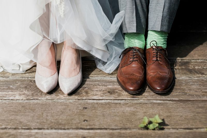 A photo of the feet and shoes of a bride and groom in their wedding attire.