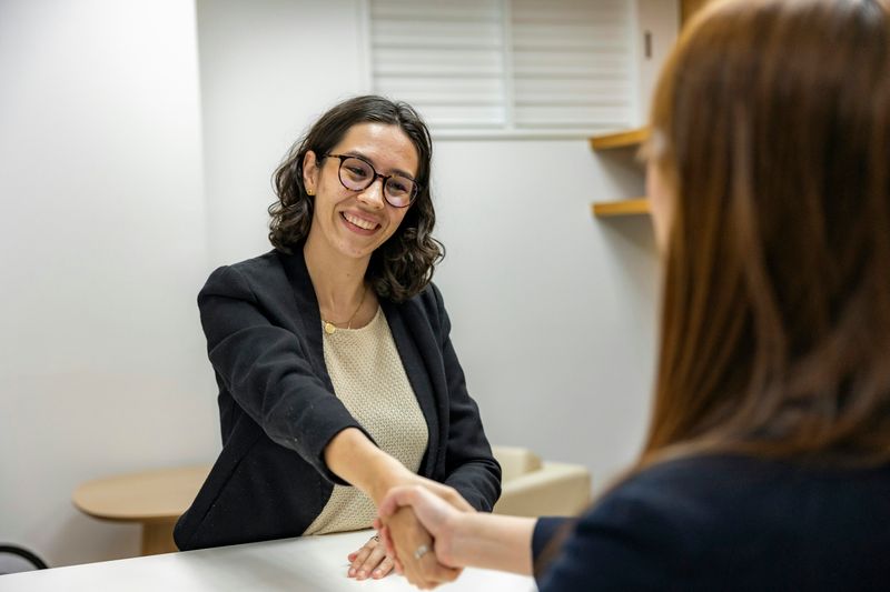 Two women in an interview, shaking hands.