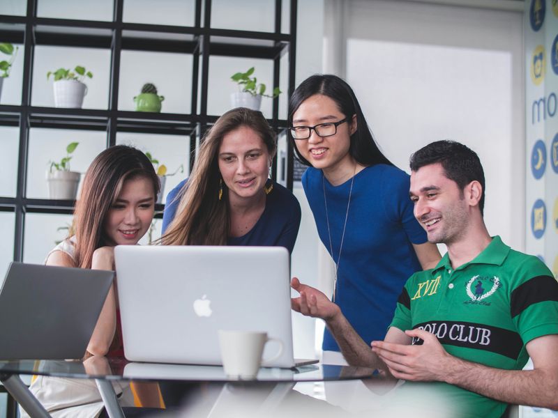 A group of young adults working together and viewing a computer screen.