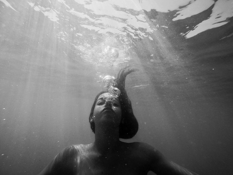 A woman underwater with air bubbles coming from her mouth. 