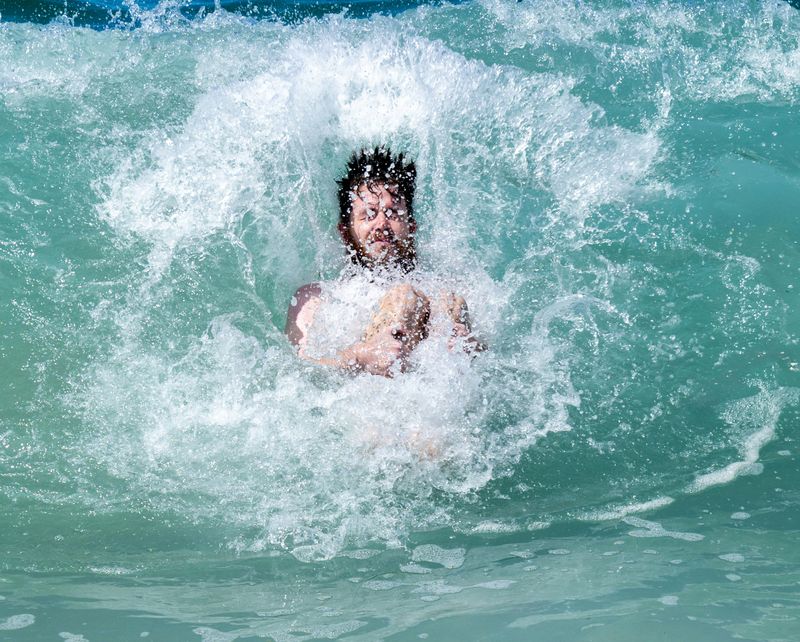 person in water with large waves with eyes closed