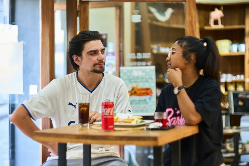 A man and a woman eating and talking over lunch in a restaurant.
