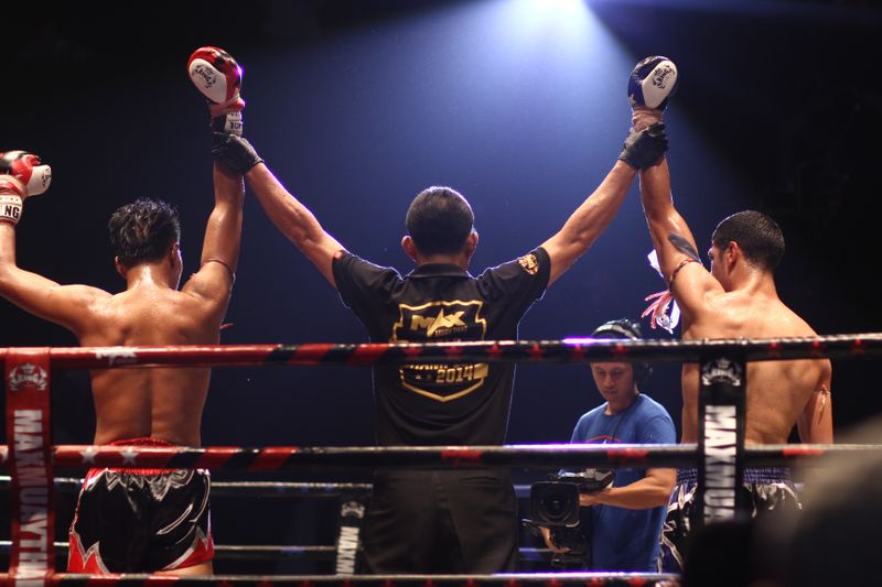 A referee holding two boxers arms up in the ring.