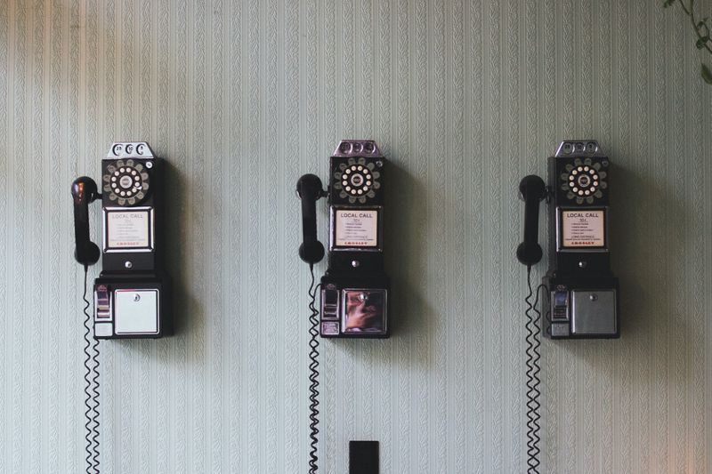 Three vintage telephones hanging on a wall.