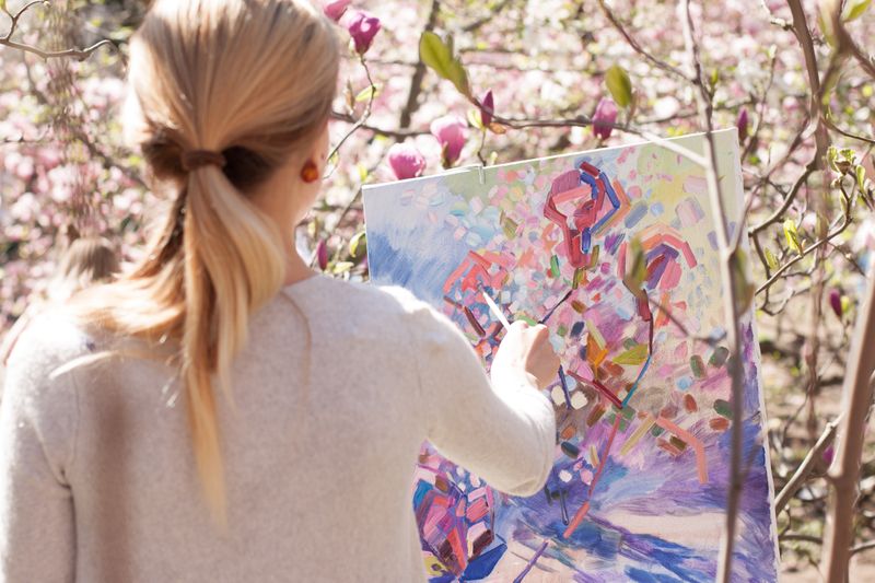 A young woman painting on a canvas.