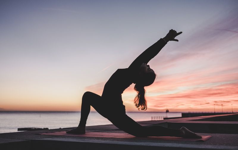 A person practicing yoga next to water.