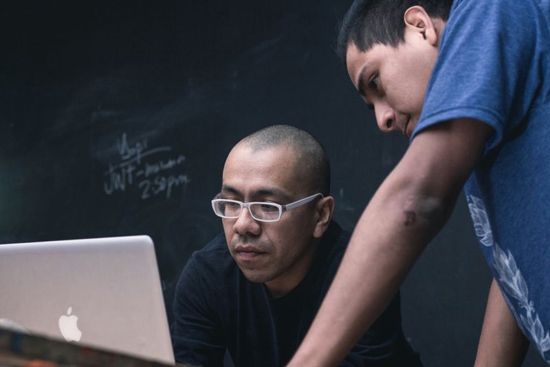A teacher and a student at work on a computer.