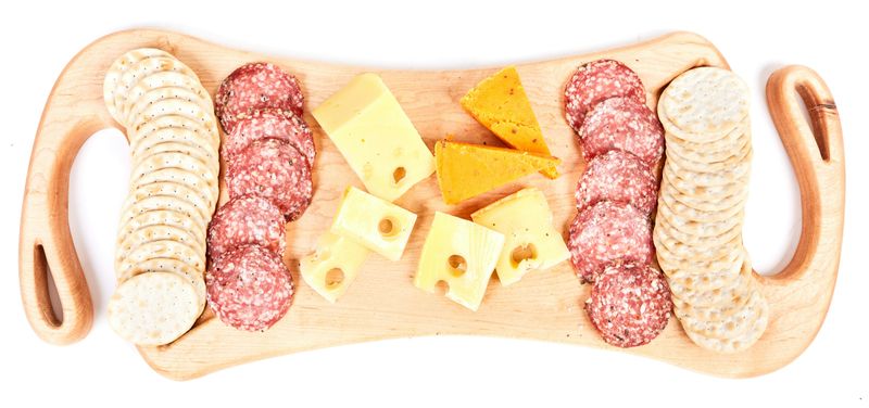 Wooden food board: crackers, sliced meat, cheese 