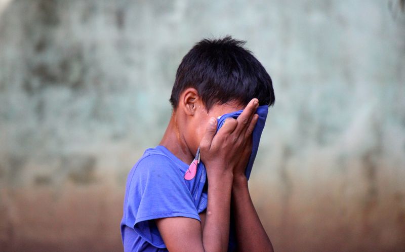 A child pulling their t-shirt over their face to hide that they're crying.