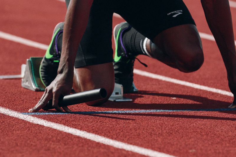 An athlete on a track field with a baton in hand, ready to run.