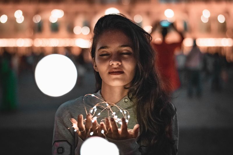 Woman with string of fairy lights in her hand.