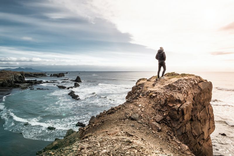 Man standing on cliff over a sea