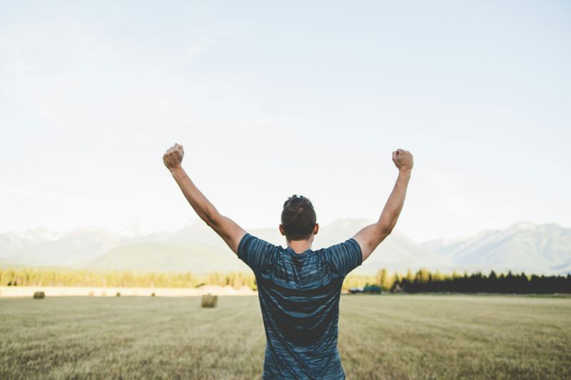 A person raises their arms in the air, excited about an achievement.