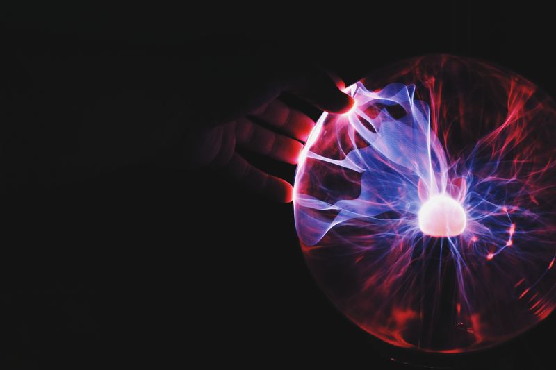 A hand touching a static electricity ball.