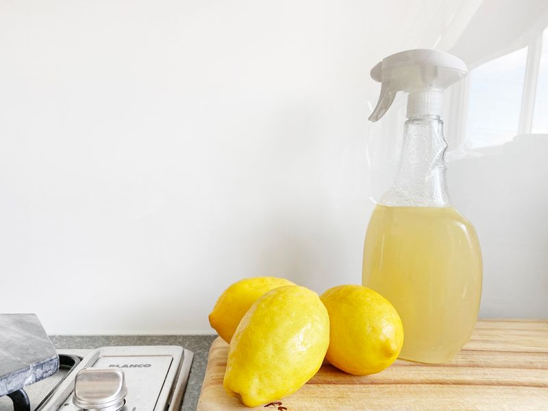 Kitchen counter with 3 lemons and bottle of yellow cleaning spray
