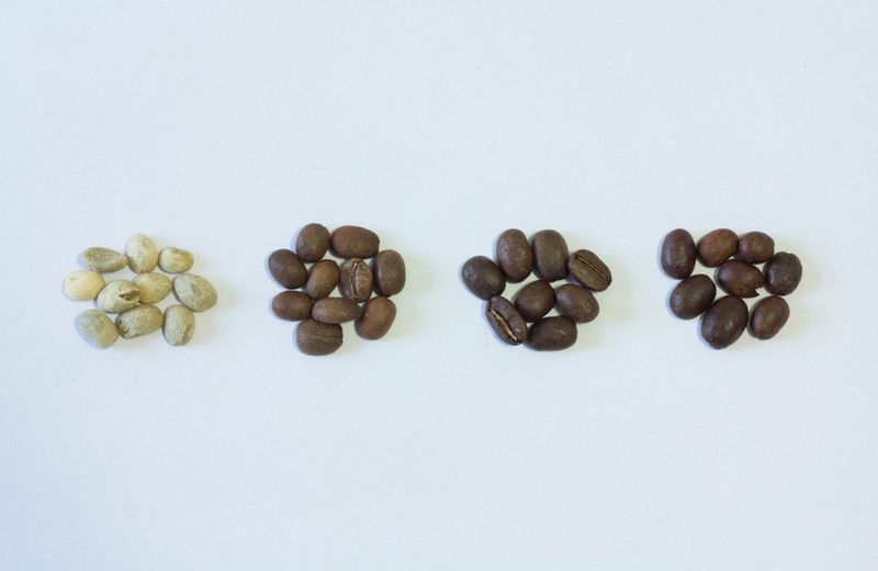 An image of different roasted coffee beans: light, medium, medium-dark, and dark