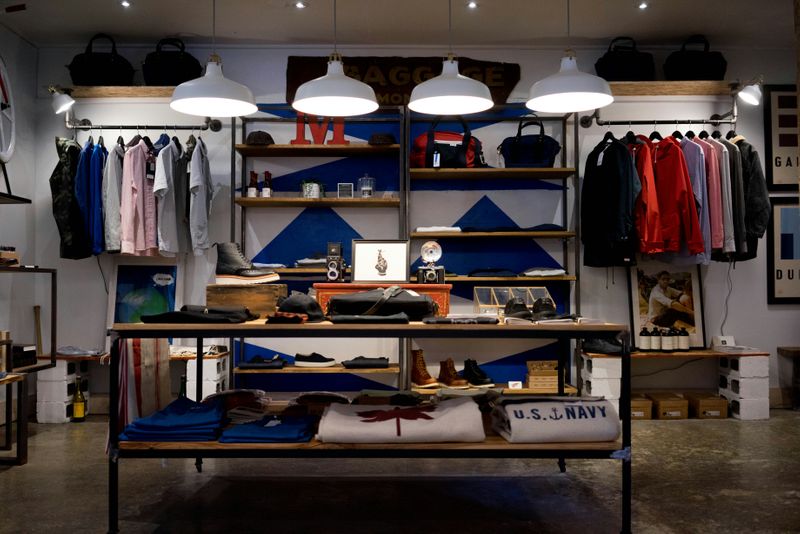A clothing store, with men's clothing items hanging off a rack and folded on shelves.