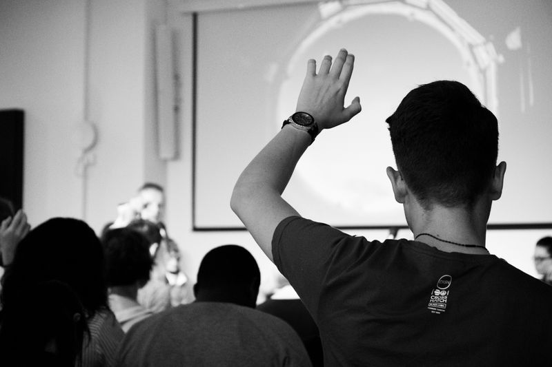 A student raising his hand in class. 