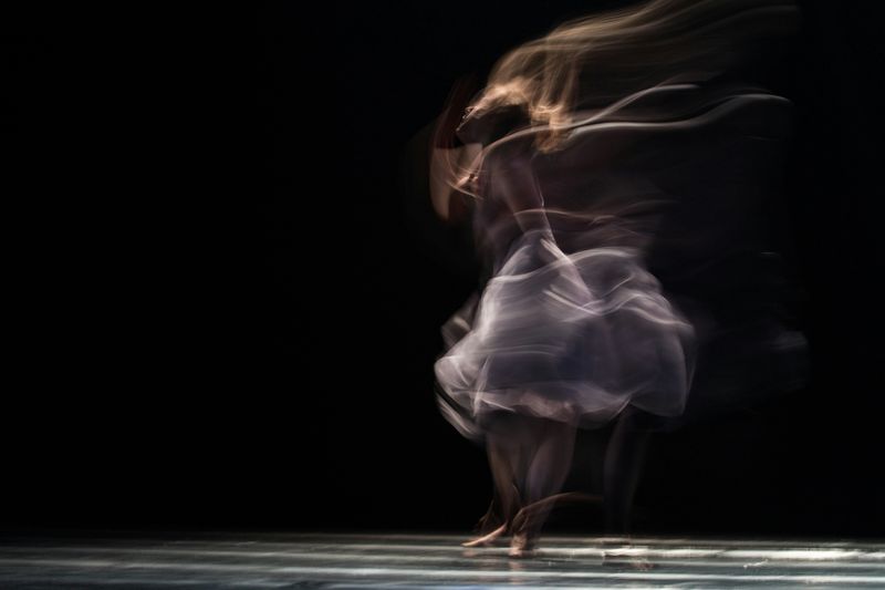 A dancer moving across stage in a blurry, fast movement.