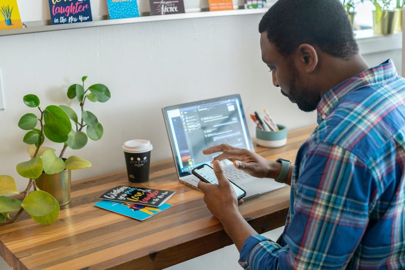 Man sitting in front of laptop while using mobile device