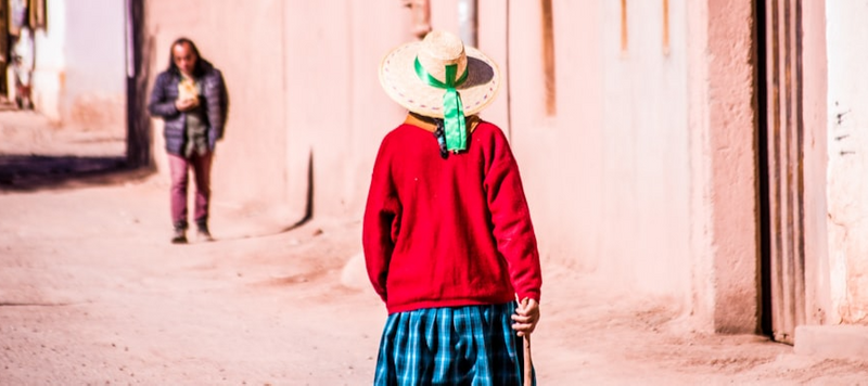 A woman walking down a sandy road.