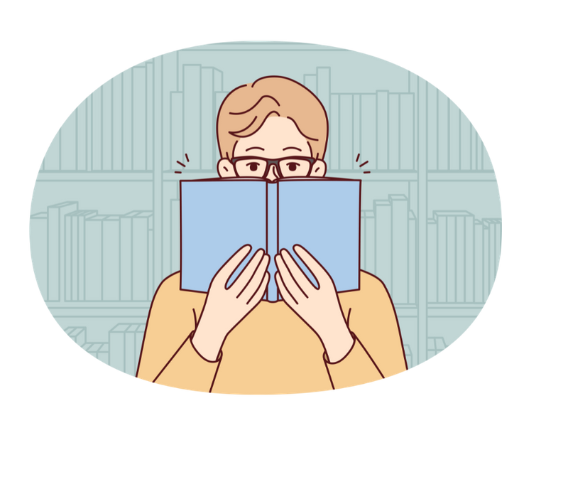 Man holds book up to his face, reading. Behind him are shelves of books.