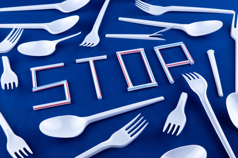 Cutlery and straws making the word stop, blue background