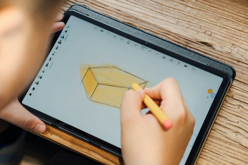 A person drawing a 3D shape on a tablet.