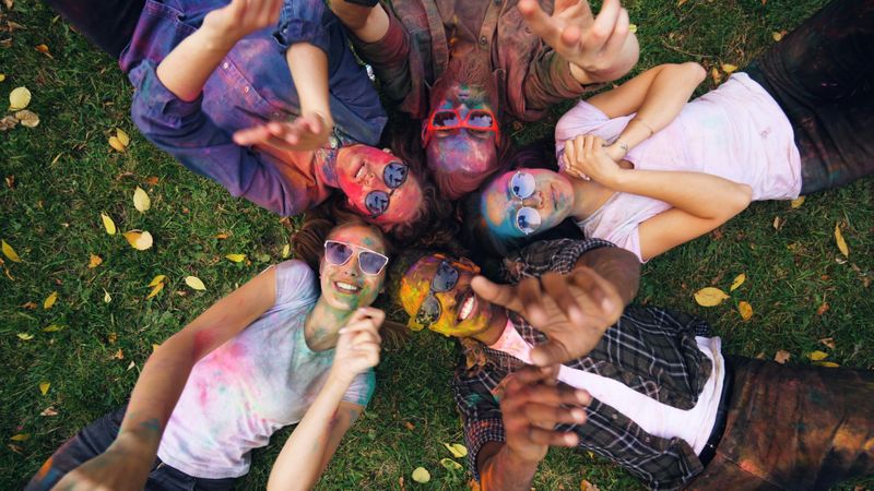 A group of people laying on grass wearing sunglasses and smiling.