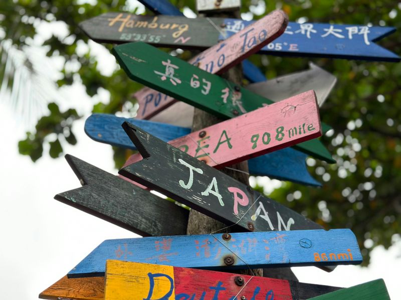 Wooden arrow signs of different countries on a pole, pointing in different directions.