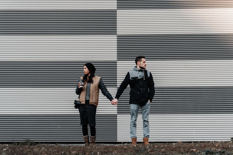 couple holds hands but look away from each other