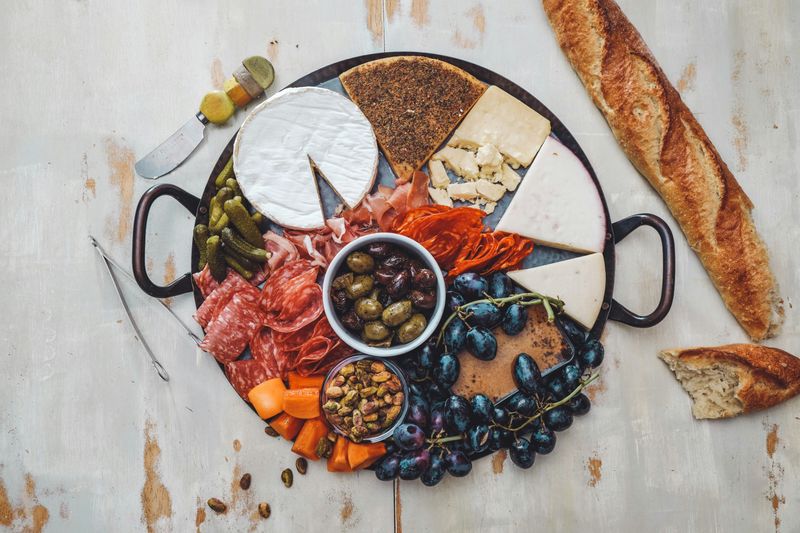 A charcuterie board with baguettes, olives, and cheeses. 