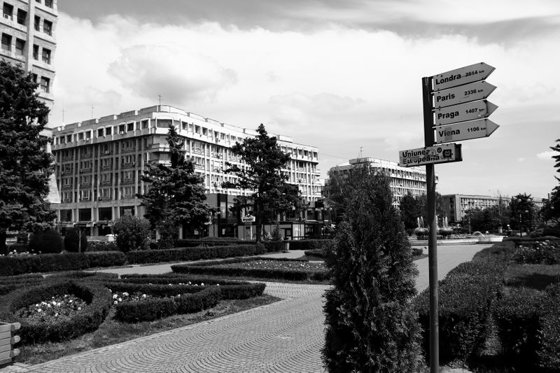 Landscaped space with sidewalks and navigation sign between buildings.