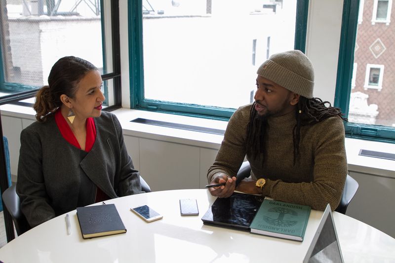 Two people at an office table discussing pain points.