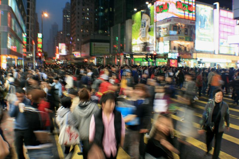 A chaotic street with a large crowd and bright city lights.