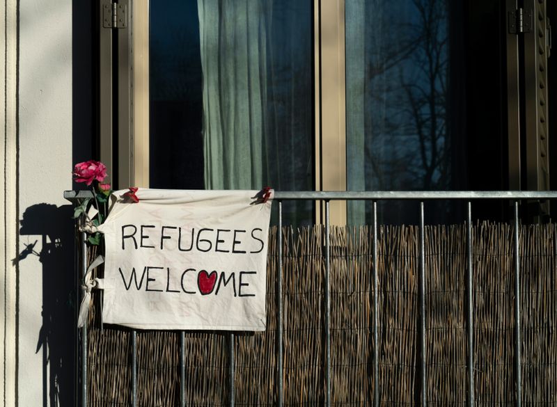 A sign that says 'Refugees Welcome'. The 'o' in 'welcome' is a heart.
