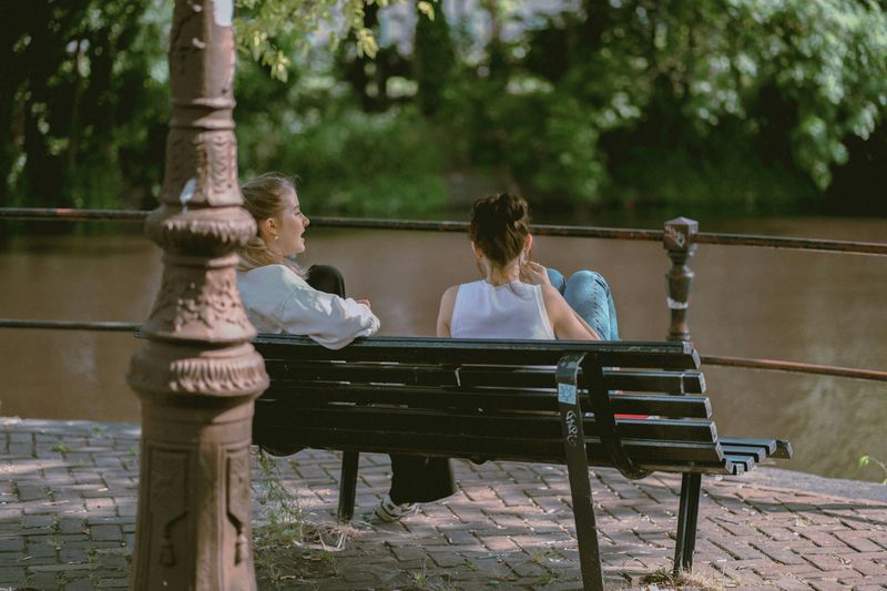 Two people on a park bench talking.