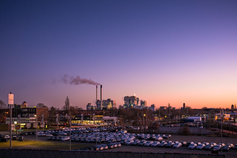 A factory's pipe smokes in the distance in a small city.