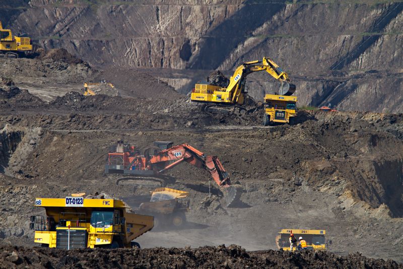 Heavy machinery mining coal in an open-air mine