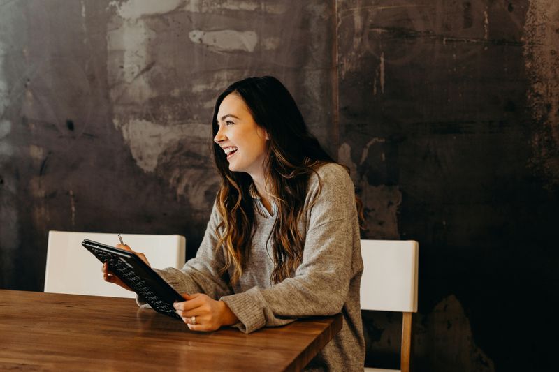 A young woman with a tablet in an office, answering an interview question.