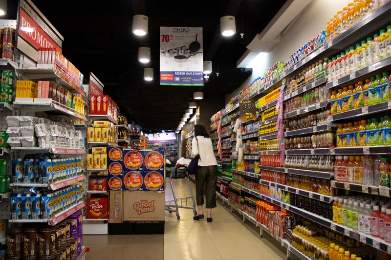 A woman pushing a shopping cart down the aisle of a grocery store