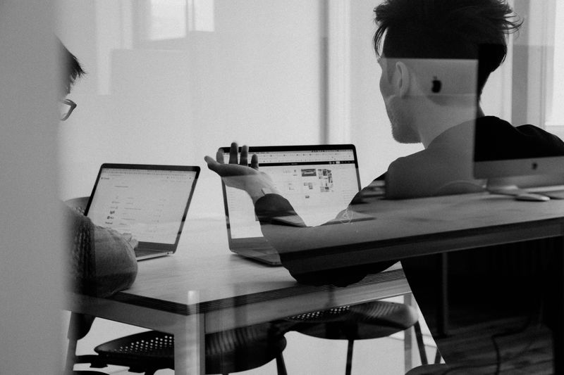 Two people discussing a project in front of their laptops.