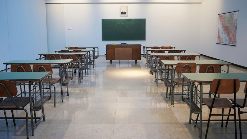 A sterile classroom with only a map on the wall and rows of desks.