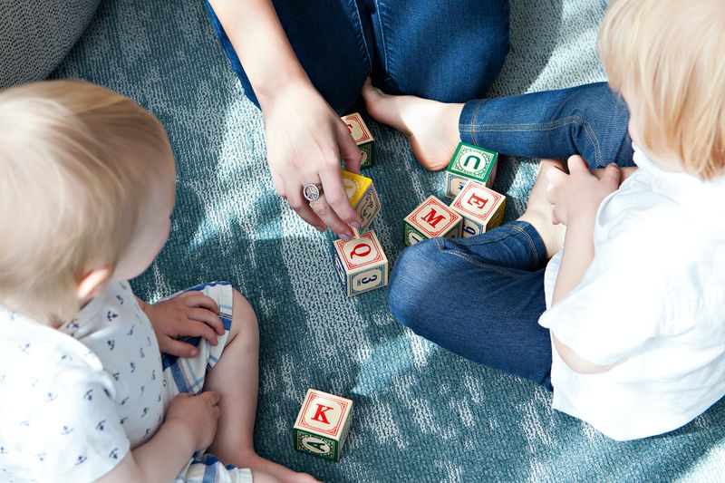 A nanny playing with children and some blocks