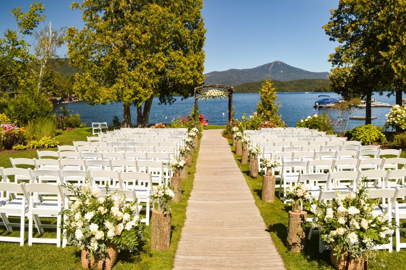 A beautiful wedding venue on a lake shore, with chairs and a stage all set up before the ceremony.