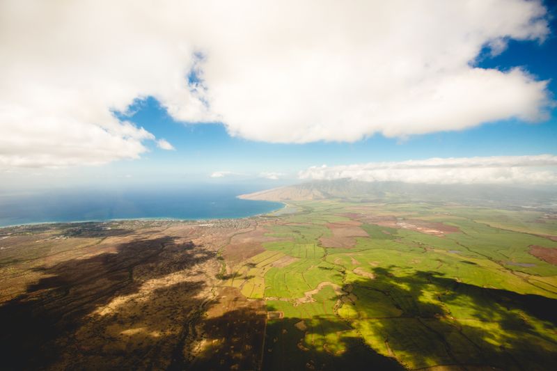 Beautiful view of land, water, sky, and clouds as seen from an airplane.